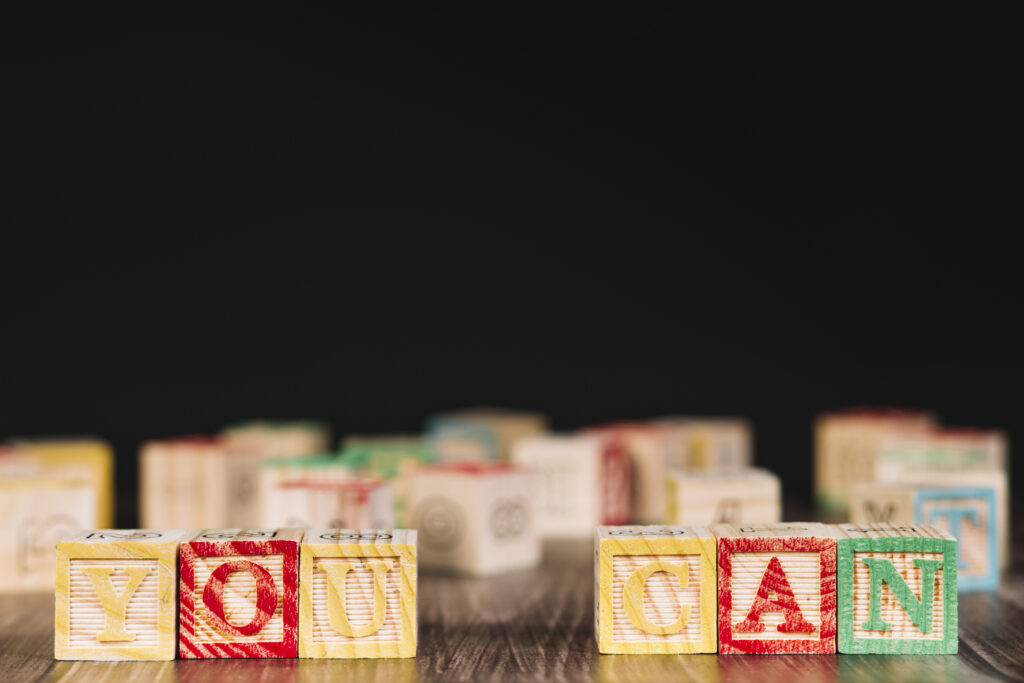 Blocs de bois alignés formant le message "YOU CAN" posé sur une table, symbole d'encouragement et de motivation.